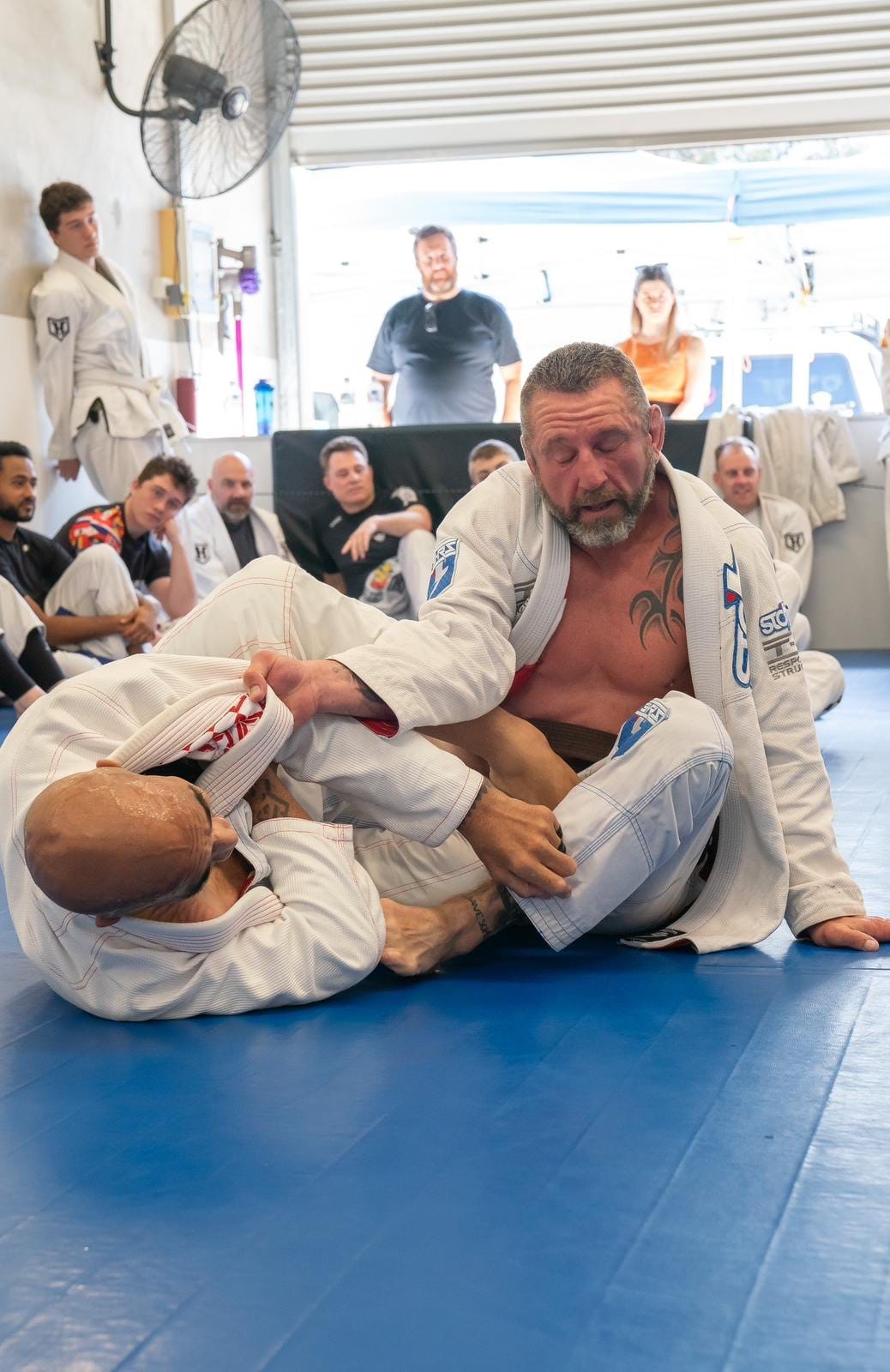 Adam Toole rolling in front of a watching crowd at his black belt grading