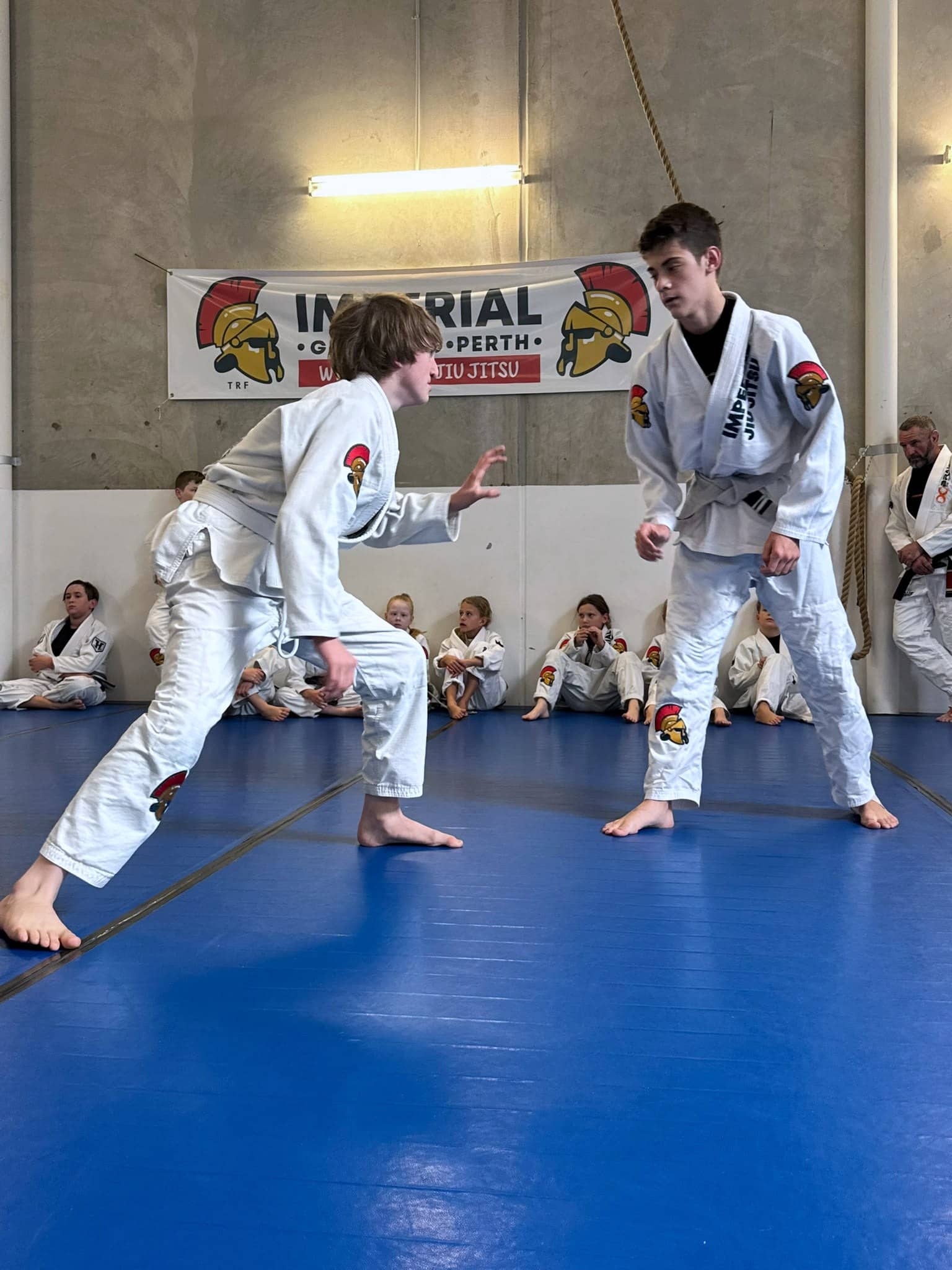 Two teenagers in gis squared off on the mats at the start of a round