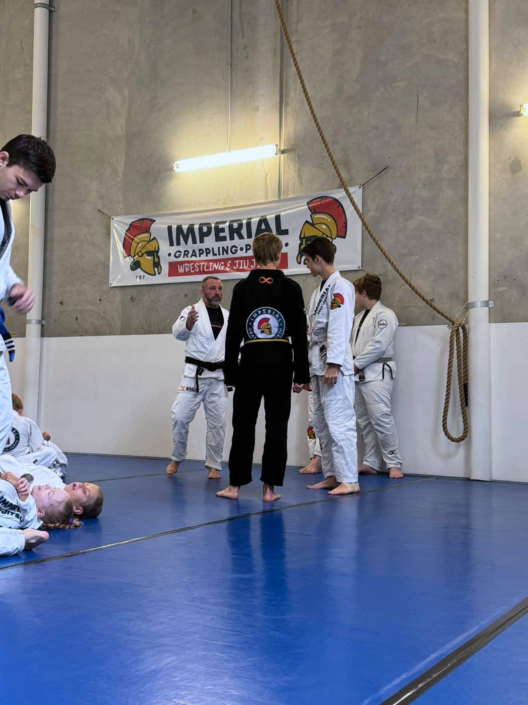 Teenagers standing between rounds at the edge of the mat